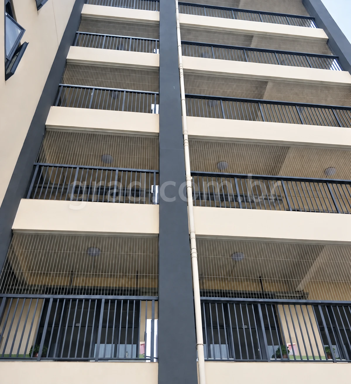 Prédio de fachada clara com proteção vertical de cabos e guarda-corpos